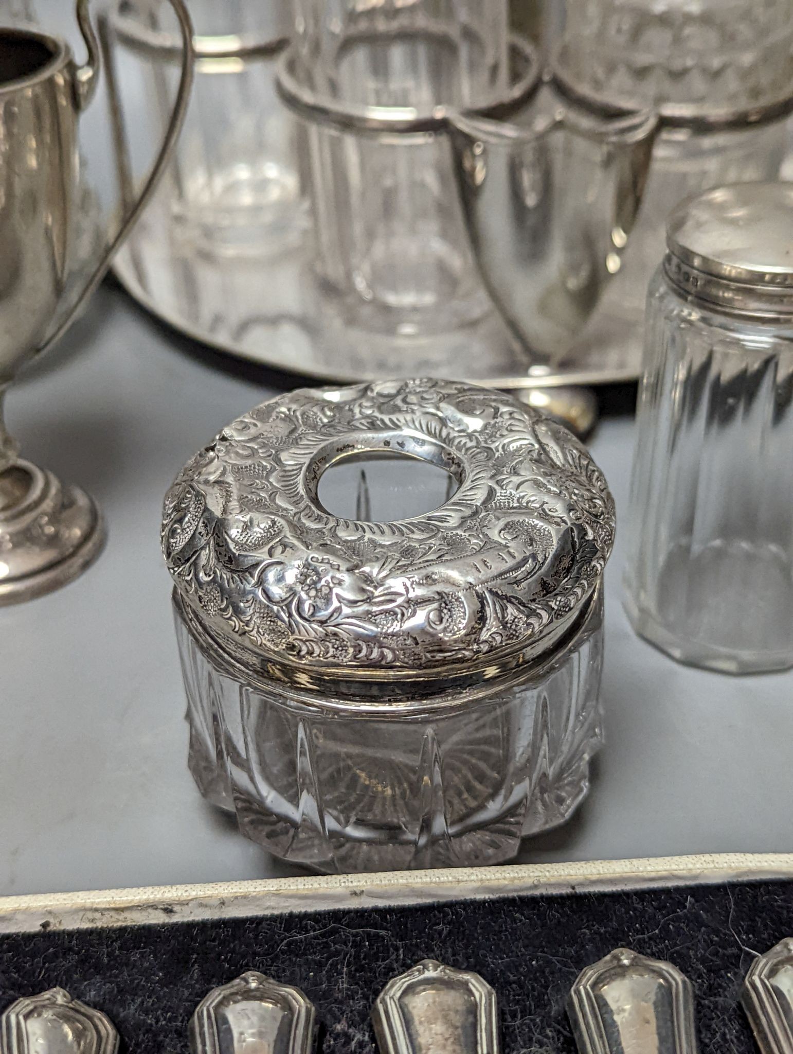 A plated cruet stand, two cased sets of silver handled tea knives, a silver domed ashtray(a.f.) silver trophy cup, four silver mounted glass jars and a plated napkin ring.